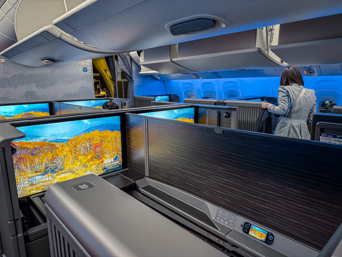 ANA First Class cabin with large TVs and blue ambient lighting.