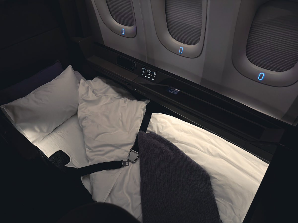 ANA First Class lie-flat bed with pillow, blanket, and comforter.