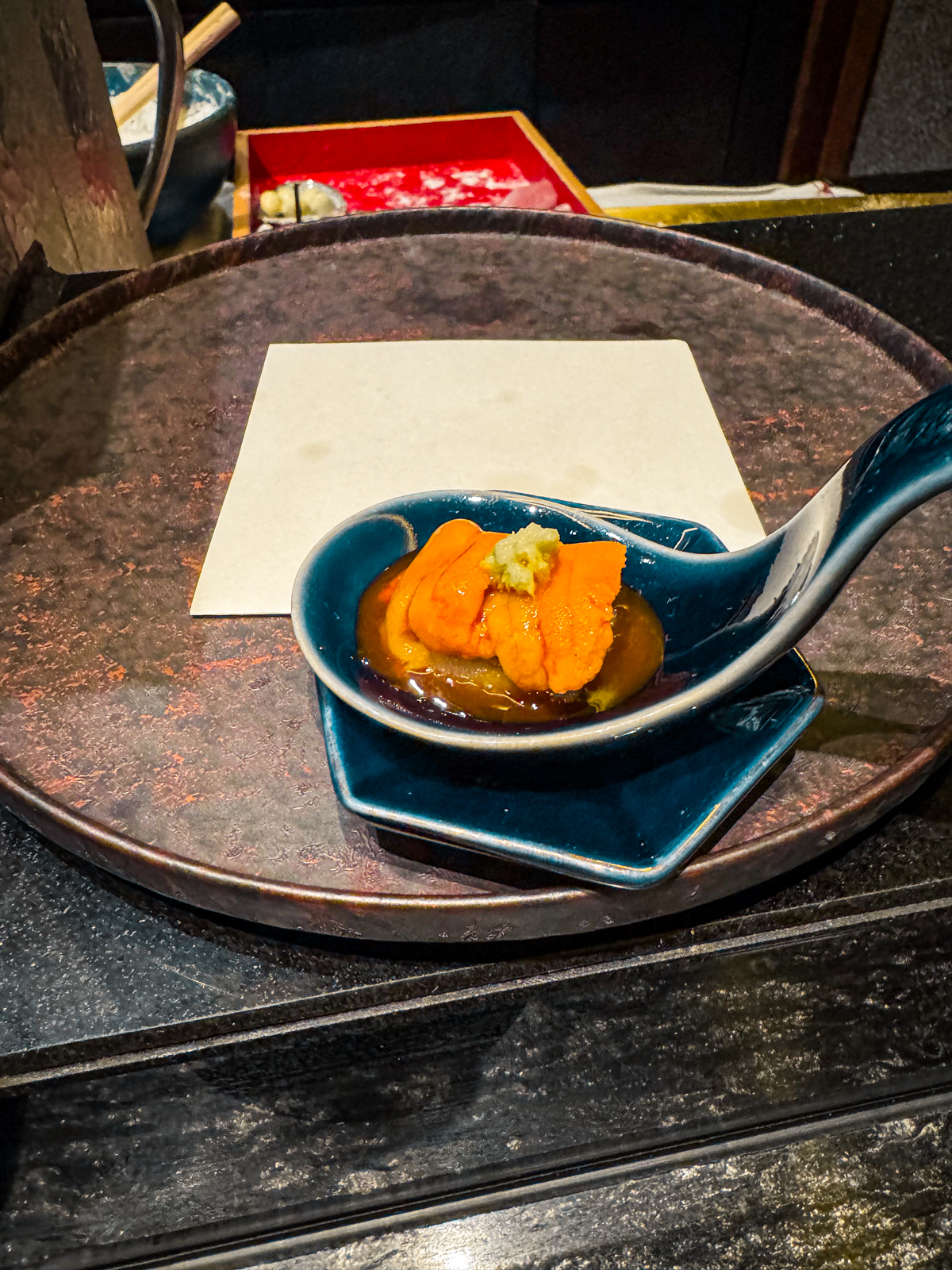 Spoon filled with uni and dashi, topped with wasabi.
