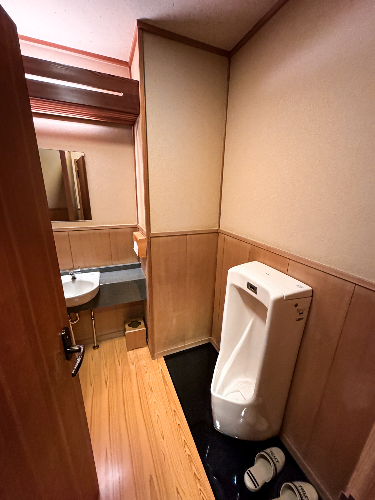 Toilet room with slippers and urinal.