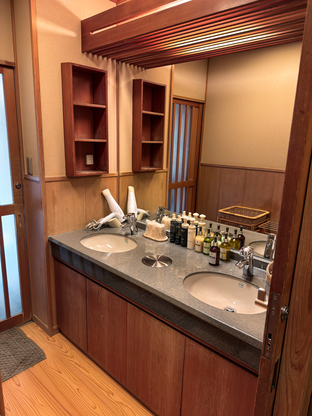 Washroom with two sinks, mirror, hair dryer, and amenities on the counter.