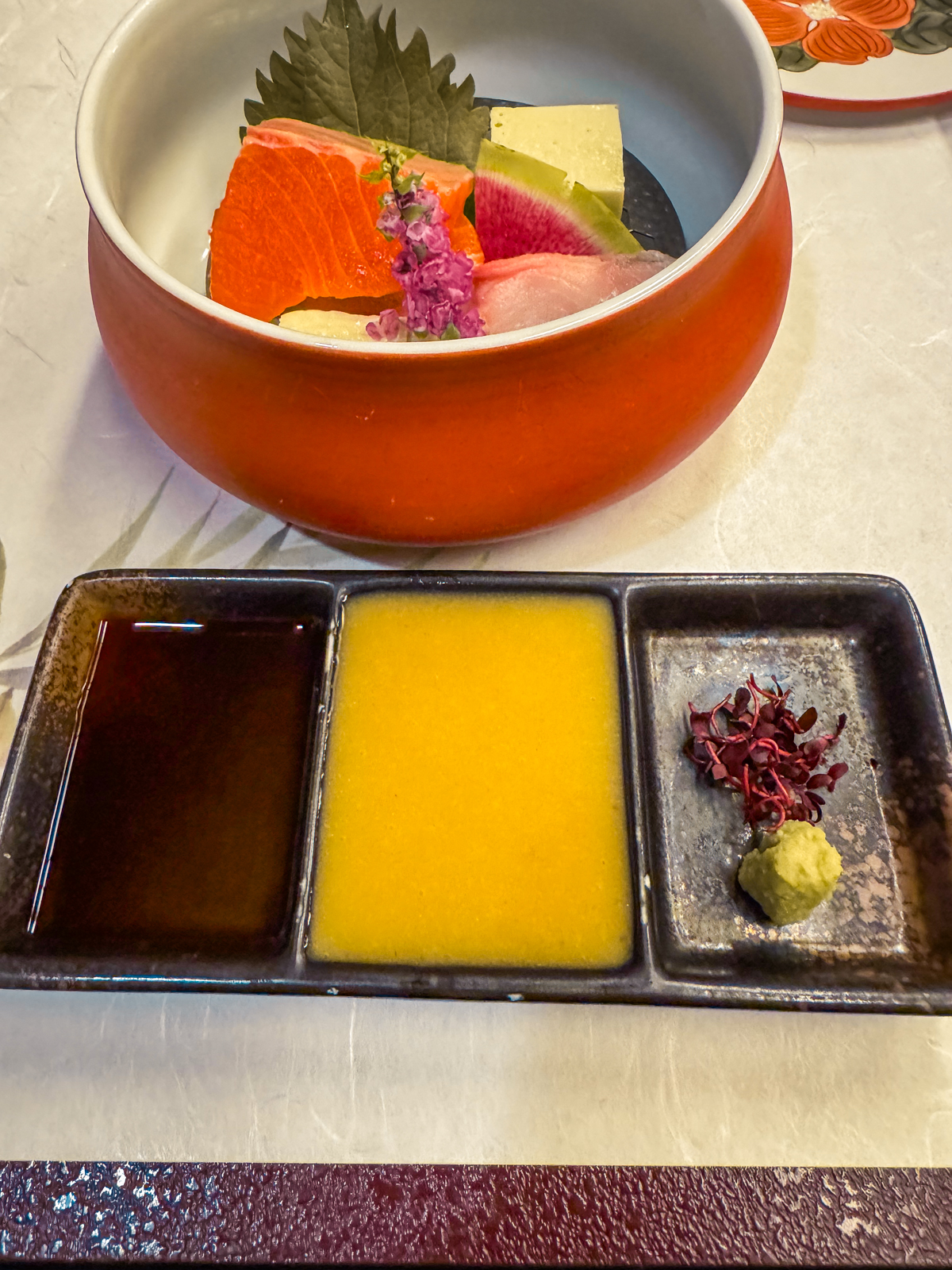 Three sauces accompanying sashimi bowl with soy sauce, a tangy yellow sauce, and wasabi.